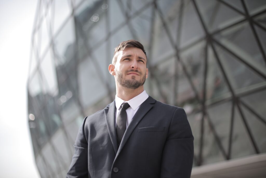 Portrait of a confident businessman in a suit standing outside a modern office building.